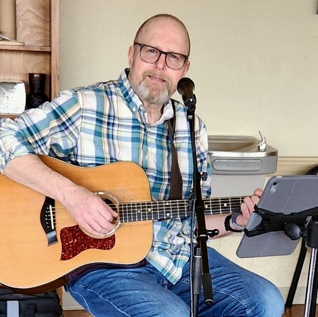 Christian Pawola singing and playing an acoustic guitar