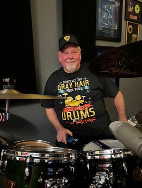 A drummer smiling behind a drum kit in the studio